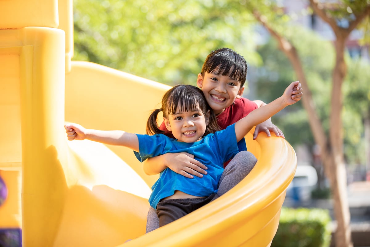 Two girls on a bright yellow slide